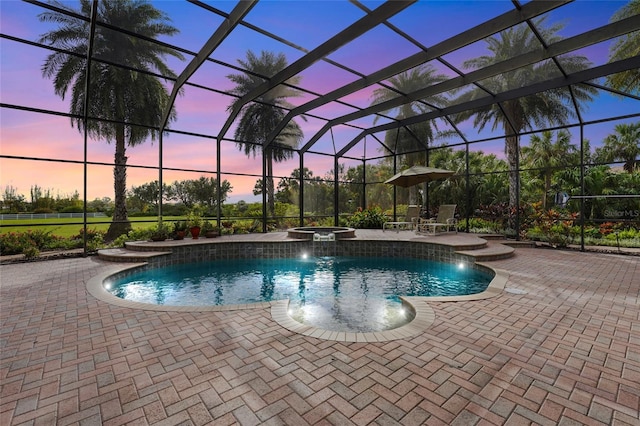 pool at dusk with a patio, a lanai, an in ground hot tub, and pool water feature