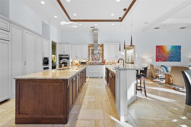 kitchen featuring a large island, a kitchen breakfast bar, wall chimney range hood, and pendant lighting