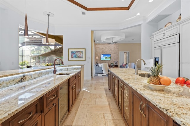 kitchen with crown molding, paneled built in refrigerator, sink, and decorative light fixtures