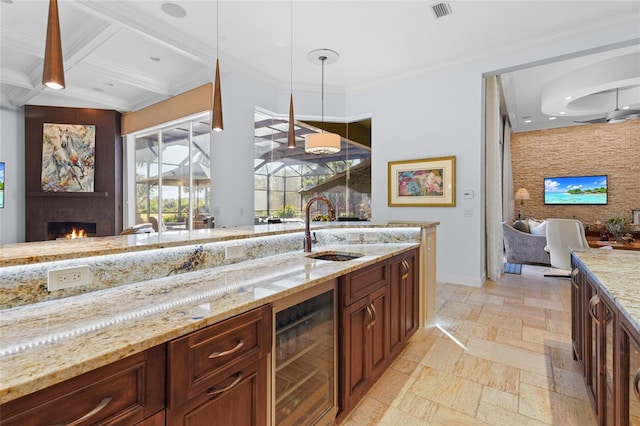 kitchen featuring light stone counters, pendant lighting, coffered ceiling, sink, and beverage cooler