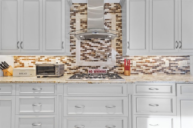 kitchen featuring decorative backsplash, stainless steel gas stovetop, and wall chimney range hood