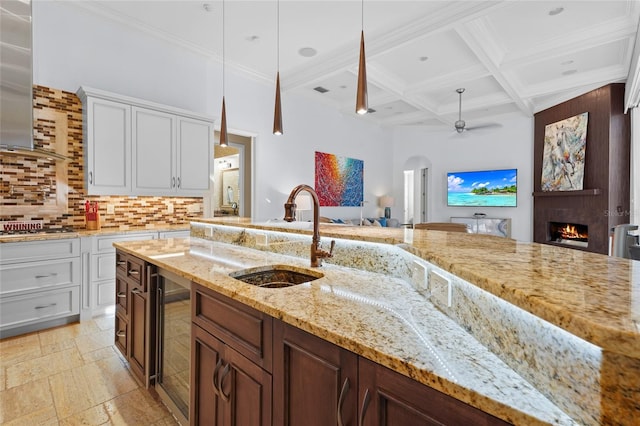 kitchen featuring decorative light fixtures, beverage cooler, sink, and white cabinets