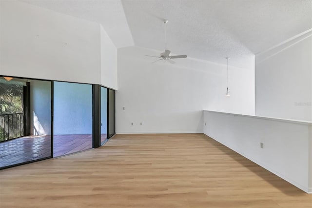 unfurnished room with ceiling fan, high vaulted ceiling, a textured ceiling, and light hardwood / wood-style floors