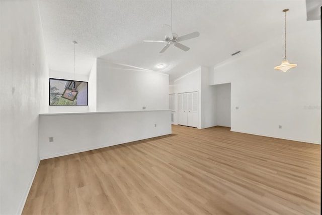 unfurnished living room featuring ceiling fan, lofted ceiling, a textured ceiling, and light wood-type flooring