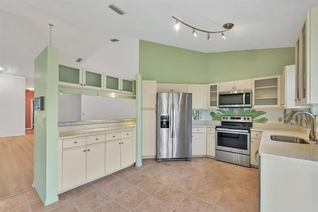 kitchen with light tile patterned flooring, sink, high vaulted ceiling, appliances with stainless steel finishes, and decorative backsplash