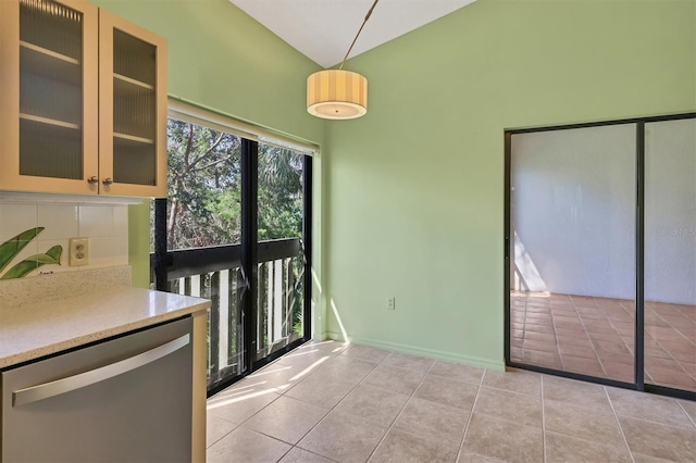 kitchen featuring light tile patterned floors, hanging light fixtures, backsplash, vaulted ceiling, and stainless steel dishwasher