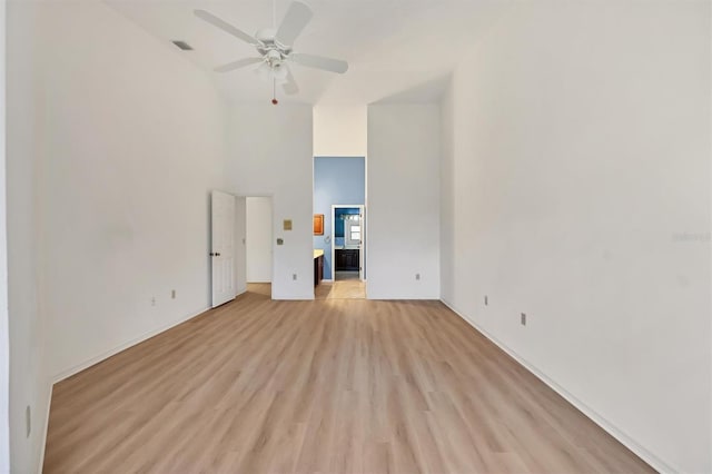 interior space with ceiling fan, a towering ceiling, and light hardwood / wood-style floors