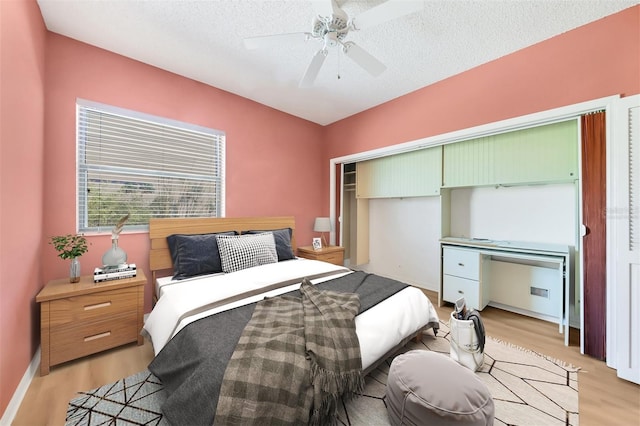 bedroom featuring ceiling fan, light hardwood / wood-style flooring, a closet, and a textured ceiling