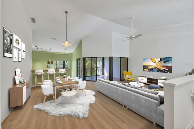 living room featuring a textured ceiling, high vaulted ceiling, and light hardwood / wood-style flooring