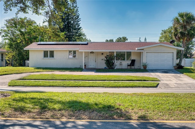 single story home featuring a garage, a front yard, and solar panels