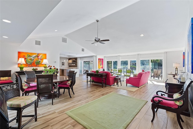 living room featuring ceiling fan, light hardwood / wood-style flooring, high vaulted ceiling, and a healthy amount of sunlight