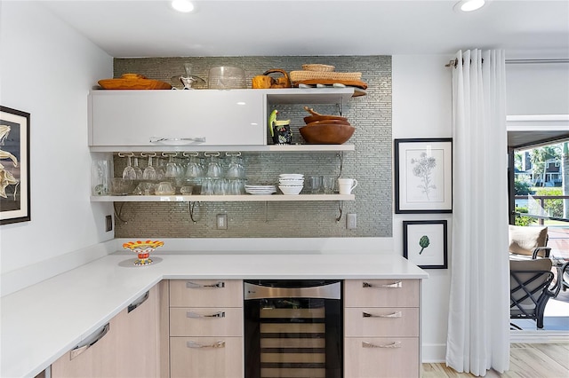 bar featuring white cabinetry, light brown cabinets, beverage cooler, light hardwood / wood-style flooring, and decorative backsplash