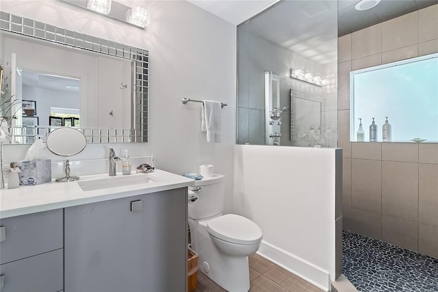 bathroom featuring tile patterned flooring, vanity, toilet, and a tile shower