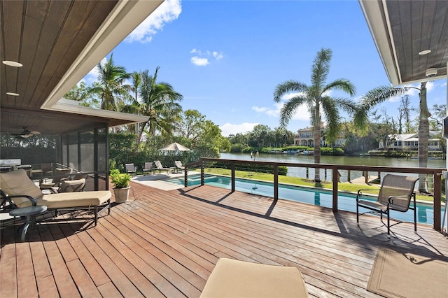 wooden deck with a sunroom, ceiling fan, and a water view