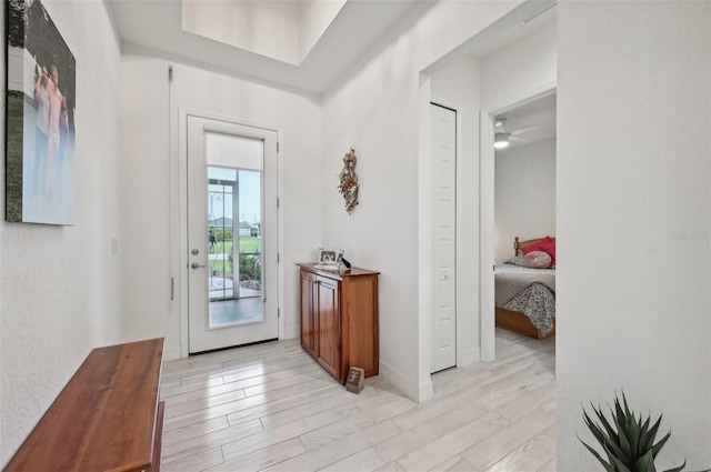 doorway to outside with ceiling fan and light wood-type flooring