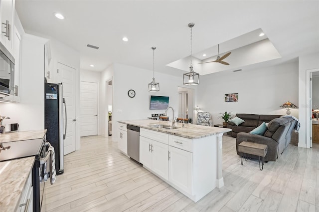 kitchen with appliances with stainless steel finishes, sink, a center island with sink, decorative light fixtures, and white cabinets