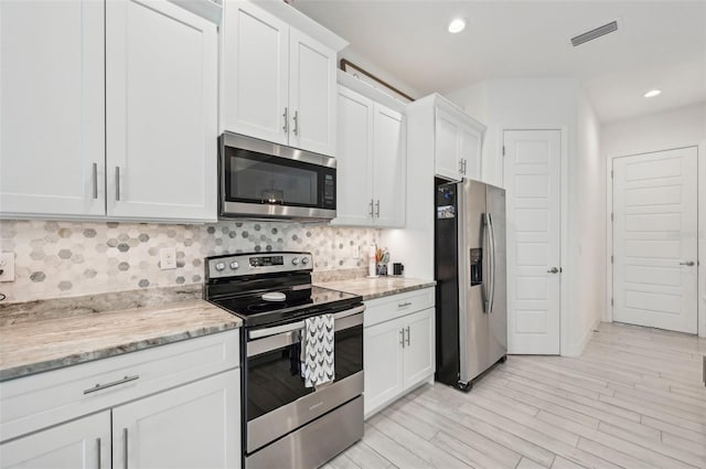 kitchen featuring light stone counters, light wood-type flooring, white cabinetry, and stainless steel appliances