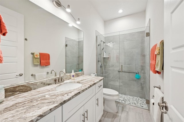 bathroom featuring vanity, toilet, and a shower with door