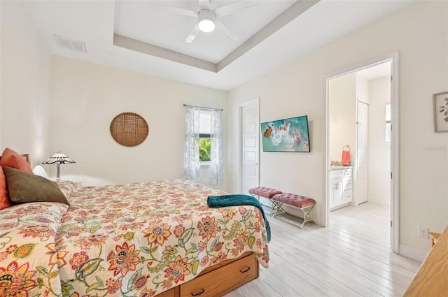 bedroom featuring ceiling fan, ensuite bathroom, and light wood-type flooring