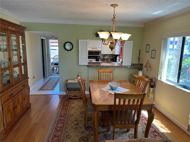 dining room with ornamental molding, a textured ceiling, light hardwood / wood-style floors, and a notable chandelier