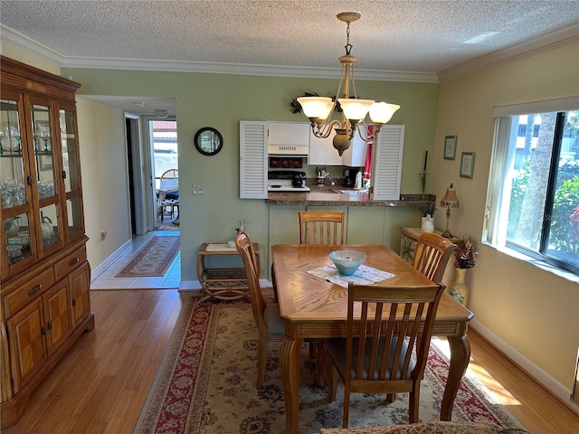 3500 El Conquistador Pkwy Unit 331, Bradenton, FL 34210 - dining room featuring a chandelier, light wood-style floors, a textured ceiling, ornamental molding, and baseboards