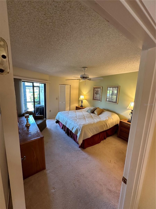 bedroom with a textured ceiling, carpet floors, and ceiling fan