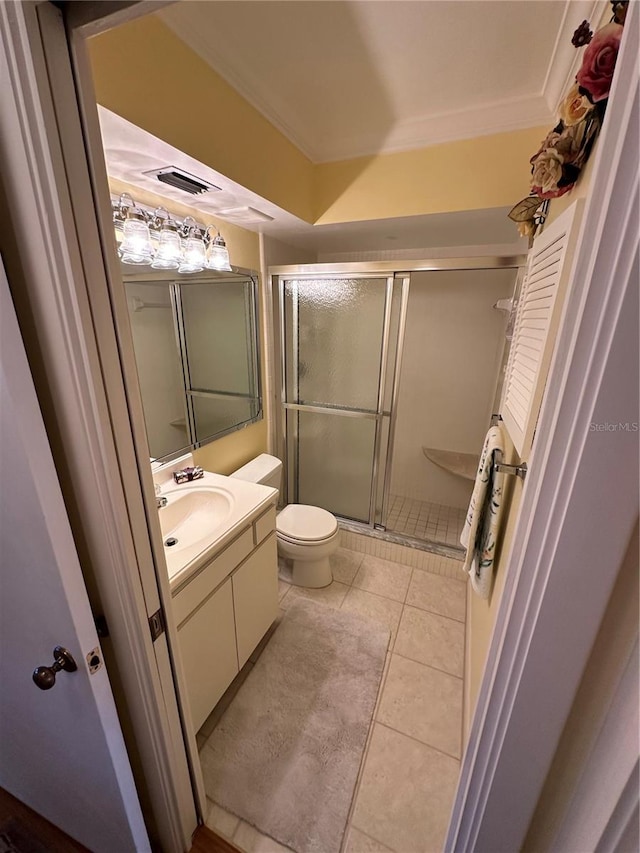 bathroom featuring vanity, a shower with door, tile patterned floors, crown molding, and toilet