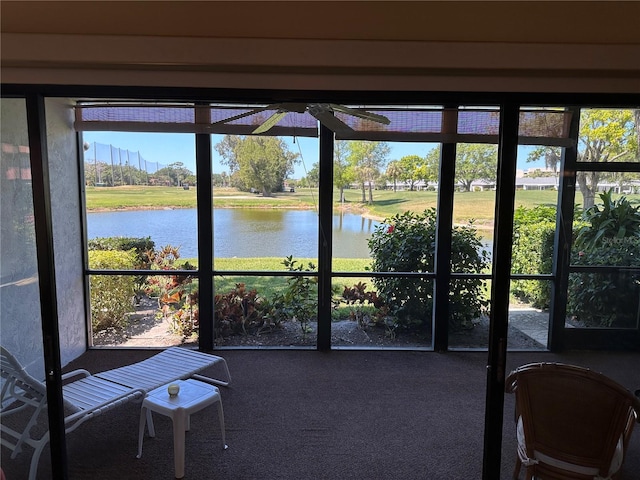 unfurnished sunroom featuring ceiling fan and a water view