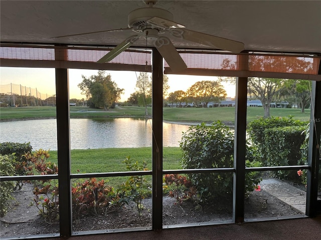 unfurnished sunroom featuring ceiling fan and a water view