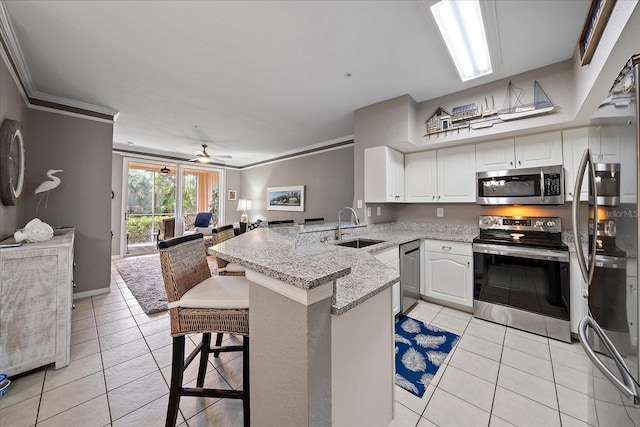 kitchen with stainless steel appliances, white cabinetry, sink, a breakfast bar, and kitchen peninsula