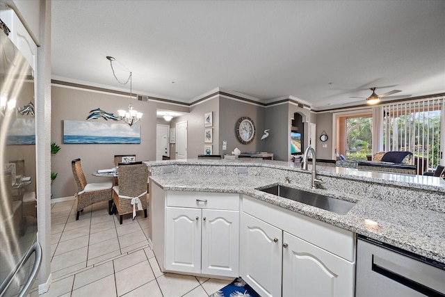 kitchen with ceiling fan with notable chandelier, white cabinets, sink, crown molding, and light stone countertops