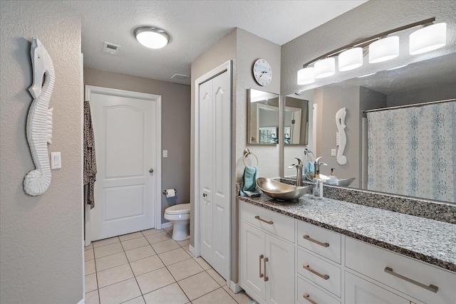 bathroom featuring vanity, tile patterned floors, a textured ceiling, and toilet