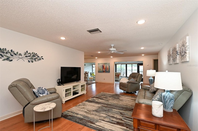 living room featuring a textured ceiling, hardwood / wood-style flooring, and ceiling fan