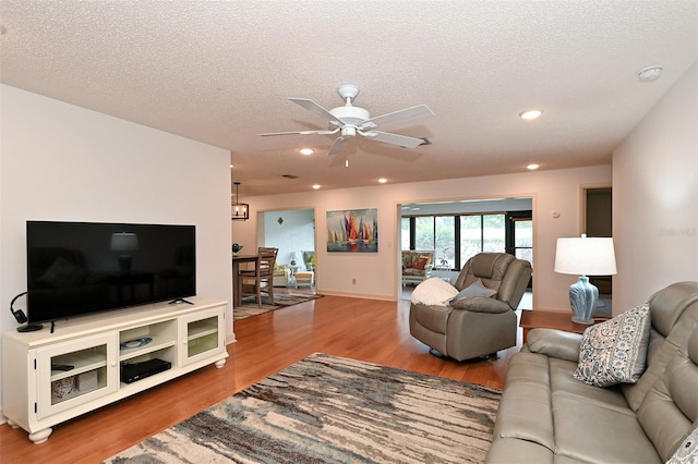 living room with hardwood / wood-style floors, ceiling fan, and a textured ceiling