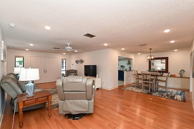 living room featuring light wood-type flooring, a textured ceiling, and ceiling fan