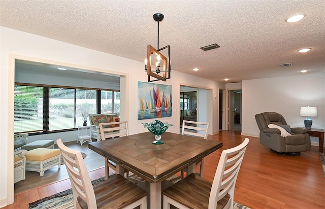 dining space featuring hardwood / wood-style floors, a chandelier, and a textured ceiling