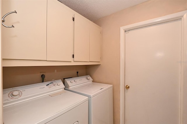 clothes washing area with cabinets, washer and clothes dryer, and a textured ceiling