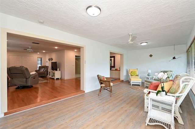 living area with a textured ceiling and light hardwood / wood-style flooring