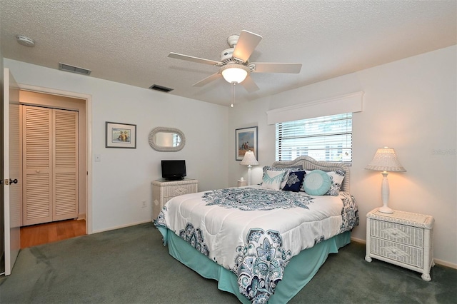 carpeted bedroom featuring ceiling fan and a textured ceiling