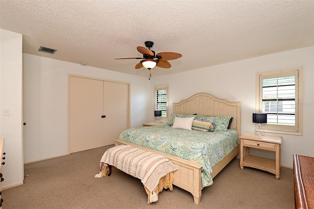 carpeted bedroom featuring a closet, a textured ceiling, and ceiling fan