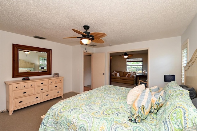 carpeted bedroom with ceiling fan and a textured ceiling