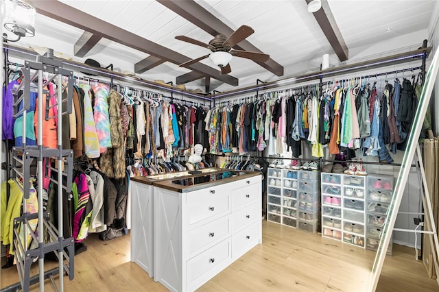 walk in closet featuring ceiling fan, light hardwood / wood-style floors, and beamed ceiling