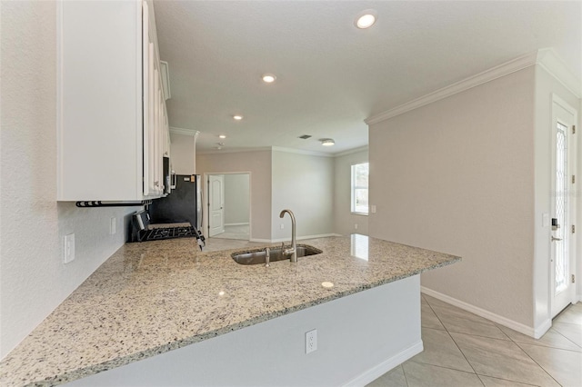 kitchen with light stone countertops, white cabinetry, sink, and kitchen peninsula