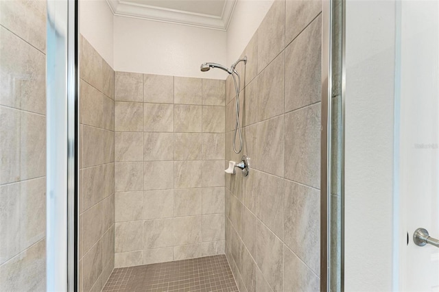 bathroom featuring a tile shower and crown molding