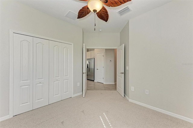 unfurnished bedroom with ceiling fan, stainless steel fridge with ice dispenser, light carpet, and a closet