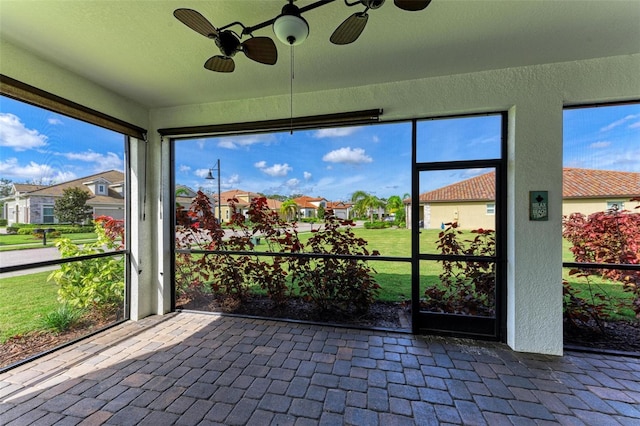 unfurnished sunroom with ceiling fan