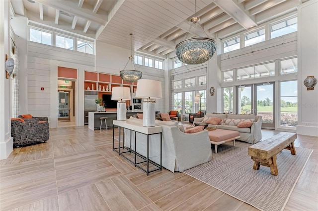 living room featuring light hardwood / wood-style flooring, beam ceiling, a wealth of natural light, and a towering ceiling