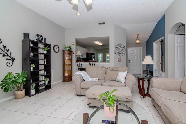 tiled living room featuring ceiling fan, a textured ceiling, and vaulted ceiling