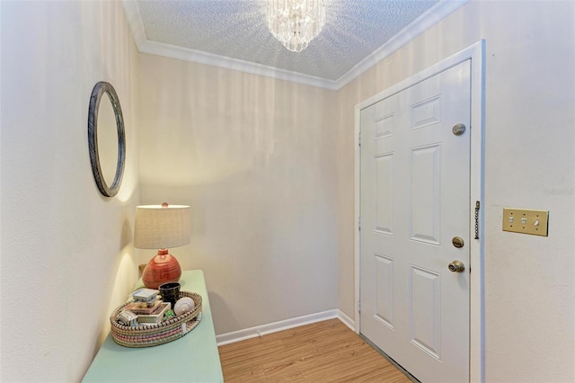 doorway featuring a notable chandelier, light wood-type flooring, ornamental molding, and a textured ceiling