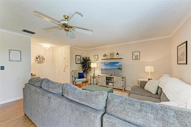 living room with ceiling fan, ornamental molding, a textured ceiling, and light hardwood / wood-style flooring